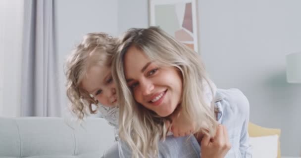 Közelkép egy csinos mosolygós gyerekről, ahogy átöleli anyát, ahogy a kamerába néz. Boldog egyedülálló anya és aranyos gyerek lány ölelés élvezze édes gyengéd szerelem koncepció. A család fogalma, a szülőség, az összetartozás. — Stock videók