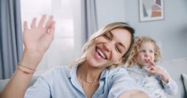 Webcam view happy blogger young mother and cute child daughter recording vlog communicating online looking at web camera and waving hand. Concept of family, parenthood, togetherness.