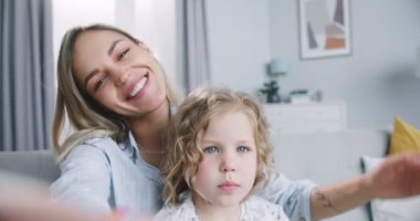 Close up of cheerful young mom and daughter talking video calling from home. Happy beautiful family adult single mother parent and cute little girl chatting online in virtual app by web camera.