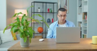 Evde dizüstü bilgisayarla özel olarak tasarlanmış bir yerde masada oturan serbest çalışan bir adam. Yorgun adam bilgisayarı kapat ve işini bitir.