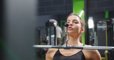 Spor salonundaki Trx fitness makinesi. Aktif, sakin, güçlü kadınların aktivite merkezinde silahlarını çalıştırmasını ve arka planda insanlarla birlikte spor salonunun gülümsemesini izledik.