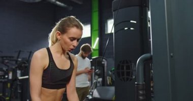 Spor salonunda trx fitness bantlarıyla kollarını çalıştıran ince kadının belden portre görüntüsü. TRX kayışlı sporcu kız spor salonunda vakit geçiriyor. Spor ve eğlence konsepti