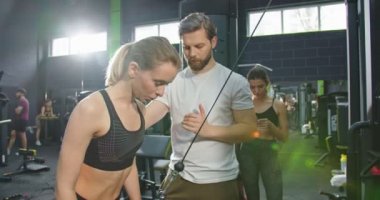 - Sonunda. Spor salonundaki uygun odada esnek halat egzersizleri yaparken beş tanesini antrenörüne veren bir kadın. Kafkasyalı genç bir kadının portresi. Vücudunu güçlendirmek için trx kayışı kullanıyor.