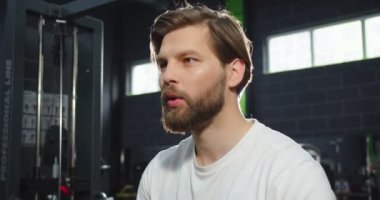 Sakallı, güçlü bir adam, kollarını kemerlerle eğitiyor, Trx. Salgın için karantina süresi boyunca spor salonunda kondisyon. Şınav çeken bir adam göğüs üst omuzlarına göğüs kasları kaslarını çalıştırıyor.