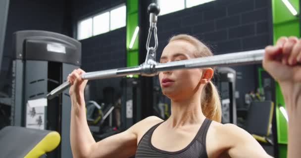Przycięty widok silnej kobiety ciężko trenującej na siłowni i ćwiczącej na urządzeniu fitness. Kobieta pracująca dla tricepsów w maszynie do krzyżowania kabli. Koncepcja reklamy siłowni — Wideo stockowe