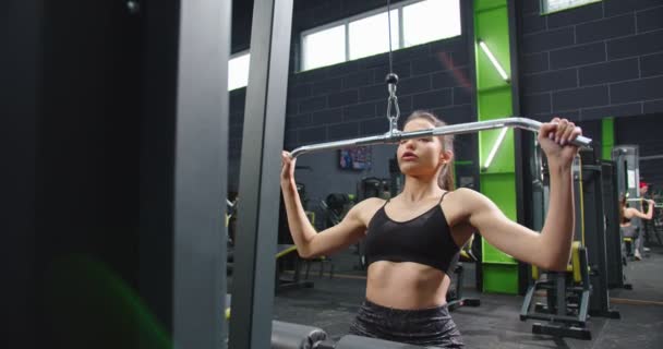 Máquina de fitness Trx en el gimnasio. Vista recortada de la calma activa fuertes brazos de entrenamiento de las mujeres en el centro de actividad con una sonrisa de placer con el gimnasio con las personas en el fondo — Vídeos de Stock