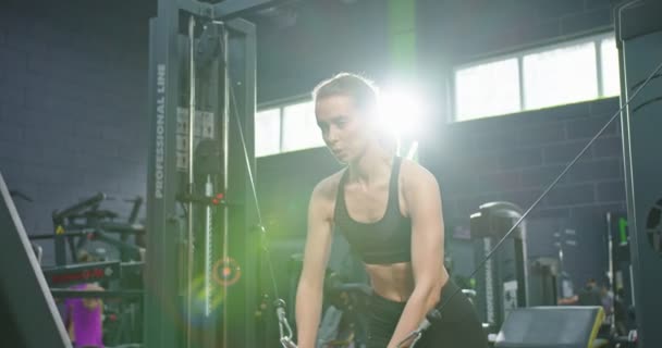 Lviv, Ukrane 04.28.2021: Profiel van de vermoeide sterke dame die haar lichaam traint met spieren. Mooie vrouw training met suspension trainer sling of vering riemen in de studio. TRX-concept — Stockvideo