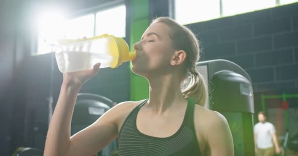 Портрет сильной здоровой женщины очень хочет пить после тренировки и отдыха во время перерыва. Женщина держит бутылку с водой и пьет. Концепция спорта и отдыха — стоковое видео
