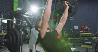 Güçlü adamın kollarını spor salonunda eğitirken özel makinede güç eğitimi aldığını gördüm. Spor ve spor konsepti