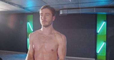 Vücut geliştirici. Spor salonunda dikilen kaslı, traşsız adam spor salonunda dambılı kaldırıyordu. Güzel sporcu erkek güç konsepti