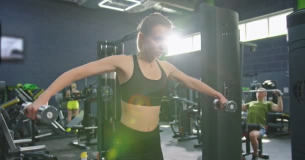 Vista completa de la chica fuerte fitness levantando mancuerna por la mañana en el gimnasio, mientras que tiene un entrenamiento duro para su cuerpo sano. Concepto de deporte y recreación — Vídeo de stock