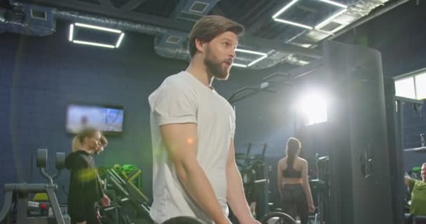 Retrato de hombre deportivo guapo con fuerte torso muscular haciendo levantamiento de pesas con la mancuerna. Ajuste a la persona que hace ejercicio con pesas durante una clase de ejercicio en un gimnasio — Vídeos de Stock