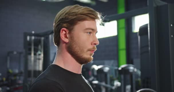 보디빌더. 건장 한 체격의 건장 한 남자가 헬스클럽에서 서 체육관에서 덤벨을 들고 있었다. 아름다운 남성 운동 선수의 힘의 개념 — 비디오