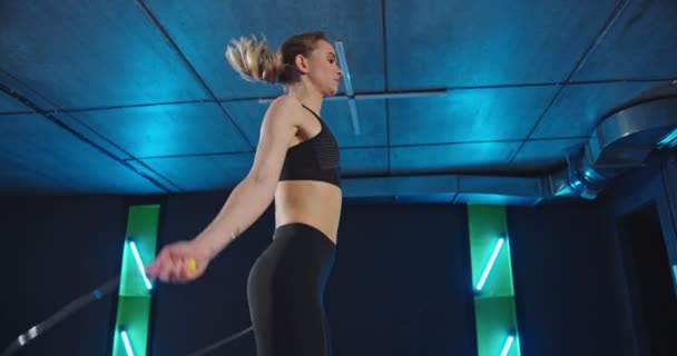 실내에서 점프 줄로 건너뛰는 젊은 여자. 여성 운동 선수가 아침에 체력 훈련을 하고 있습니다. 체육관 컨셉 안에 갇힌 채로 일하는 모습 — 비디오