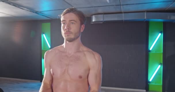 Bodybuilder. Fitness muscled unshaven man standing at the gym and lifting dumbbell at the gym. Beautiful sporty guy male power concept — Stock Video