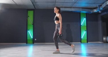 Spor salonunda zevk alarak antreman yaparken halterle atlayan güçlü ve aktif kadının tam boy görüntüsü. Stok videosu