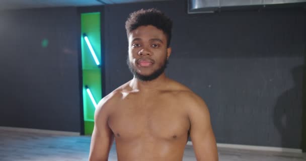 Porträtt utsikt över den trötta multiracial man ler toothy till kameran samtidigt som du kopplar av på gymmet efter hård träning. Idrott och fritid — Stockvideo