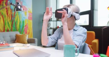 Beyaz tenli, VR gözlüklü, modern teknolojiyi kullanarak yeni bir proje üzerinde çalışan güzel bir kadının portresi. Sanal gerçeklik kulaklığı kullanan bir kadın. Teknoloji kavramı
