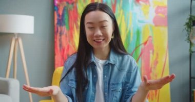 Evdeki odada oturan kameraya bakarken konuşan Asyalı güzel bir kadının portresini yakından çek. Güzel, neşeli bir kadın kameraya bir şeyler anlatıyor. Webinar, video çağrısı, vlog konsepti