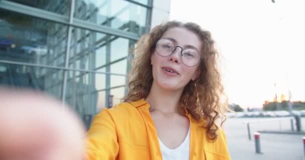 Close up portrait of happy beautiful Caucasian woman in glasses having online conversation on street with smile on face standing outdoor. POV of joyful female speaking on video chat on internet — Stock Video