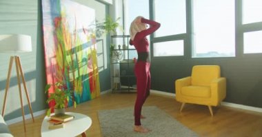 Genç ve güzel bir kadın, güçlü bir karantina oluştururken evde egzersiz yapıyor. Zayıf, formda, Müslüman bir kadın modern güneşli odada yoga ve spor yapıyor. Sporcu yaşam tarzı, spor konsepti