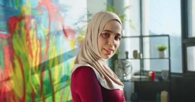 Evdeki güneşli oturma odasında durup gülümseyen bir gülümsemeyle kameraya bakan güzel bir Arap kadının portresini yakından çek. Olumlu duyguları olan Müslüman kadın.