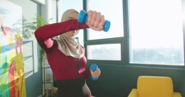 Arap güzel bir kadının evde egzersiz yaparken halterli aletleri iyi bir ruh hali içinde kullanmasını yakın çekim. Arap genç, güzel bayan atlet apartman dairesinde egzersiz yapıyor. Spor, spor konsepti