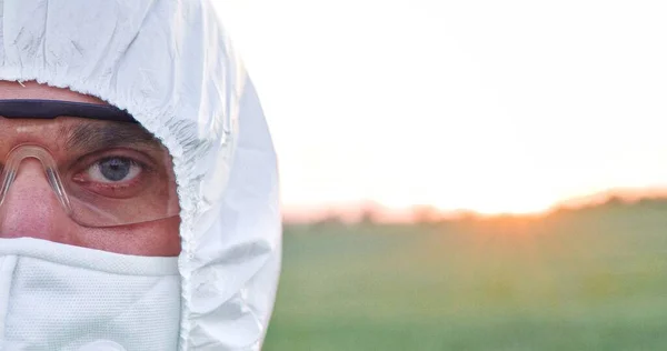 Ritratto ritagliato di contadino caucasico che indossa attrezzature protettive guardando la telecamera sul campo. Terreno agricolo tramonto paesaggio agricoltura. Terreno agricolo e concetto di cielo al tramonto — Foto Stock