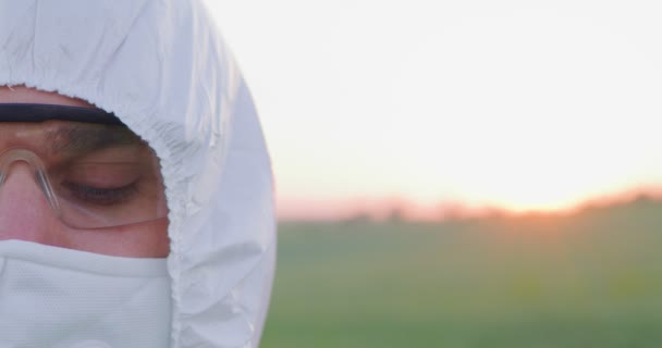 Geschnittenes Porträt eines kaukasischen Bauern, der Schutzausrüstung trägt und in die Kamera auf dem Feld blickt. Ackerland Sonnenuntergang Landschaft Landwirtschaft. Ackerland und Sonnenuntergangshimmel — Stockvideo