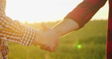 El sıkışalım. Kıdemli çiftçinin gün batımında tarlada çalışırken genç meslektaşıyla tokalaşırken çekilmiş görüntüsü. Tarım sektörü kavramı