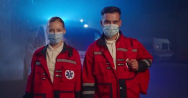 Tıbbi maskeli beyaz erkek ve kadın sağlık görevlilerinin portresi. Solunum cihazlarında kameraya bakan erkek ve kadın doktorlar. Covid-19 salgını sırasında gece doktorlar ve meslektaşları.