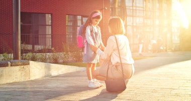 Güneşli bir günde okul bahçesinde küçük tatlı bir kızla konuşan güzel bir kadın. Kafkasyalı mutlu anne derslerden önce kız öğrenciyle dışarıda sohbet ediyor. Okul konseptine dönelim.