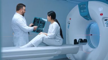 Doktor MR taramasını analiz ediyor. Doktor tomografi taraması yapıyor ve hastayla konuşuyor. Hasta tomografide oturuyor. Doktor MRI işleminin sonucunu belirliyor. Manyetik rezonans görüntüleme.