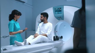 Profesyonel radyolog tablet kullanıyor. Tıp merkezinde MRI cihazını kullanarak tanı koymadan önce hastaya danışmanlık yapıyor. Hasta röntgen işleminden önce doktordan tavsiye alıyor..