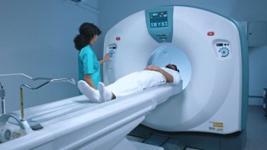 Nörocerrah, modern hastanede pozitron emisyon tomografisi incelemesi sırasında MRI tarayıcısının ayarlarına basar. Tıbbi ekipman: tanı kliniğinde bilgisayarlı tomografi makinesi.