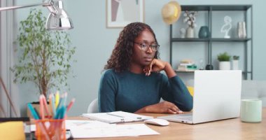 Odada masa başında oturup planlama yaparken dizüstü bilgisayarla çalışan konsantre olmuş güzel Afro-Amerikan kız portresi. Kapalı alanda bilgisayarda yazan ve yazan bir kadın. Konsept çalış