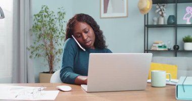 Masada oturup bilgisayarda yazarken akıllı telefondan konuşan güzel, ciddi bir kız. Cep telefonuyla sohbet eden ve dizüstü bilgisayarla mesajlaşan Afro-Amerikan kadın portresi. Kapalı alan kavramı