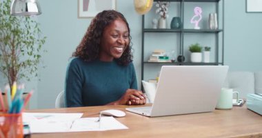 Neşeli, güzel bir kadın evde otururken elini sallıyor ve bilgisayar başında konuşuyor. Odada dizüstü bilgisayarla sohbet eden Afro-Amerikan mutlu kız portresi. Boş zaman konsepti