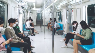 Kalabalık bir metroda maske takan insanlar.
