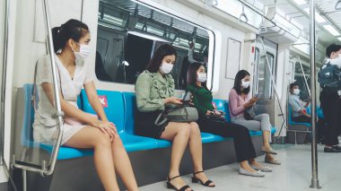 Kalabalık bir metroda maske takan insanlar.