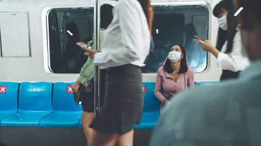 Kalabalık bir metroda maske takan insanlar.