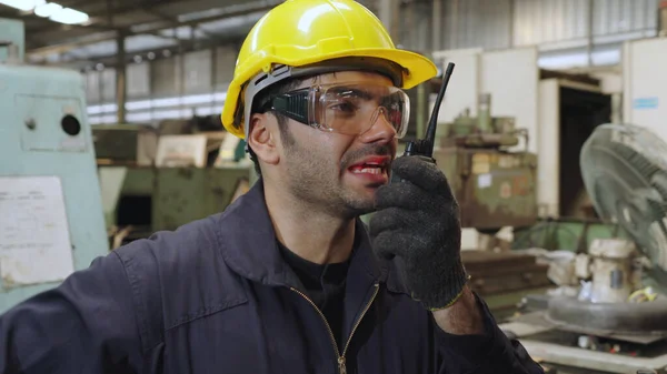 Travailleur d'usine parlant à la radio portable tout en inspectant les pièces de machines — Photo