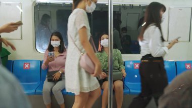 Kalabalık bir metroda maske takan insanlar.