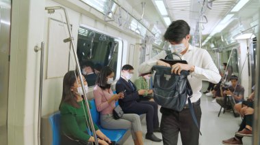 Kalabalık bir metroda maske takan insanlar.