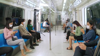 Kalabalık bir metroda maske takan insanlar.