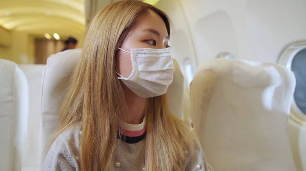 Reiziger draagt gezichtsmasker tijdens het reizen met een commercieel vliegtuig . — Stockfoto