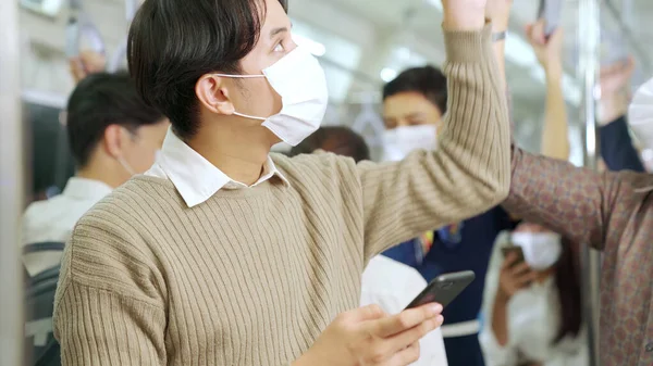 Pelancong mengenakan masker wajah saat menggunakan ponsel di kereta api umum — Stok Foto