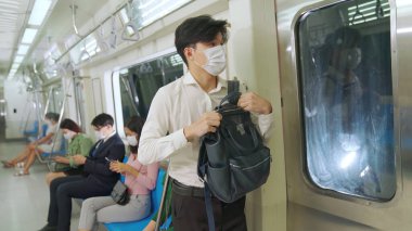 Kalabalık bir metroda maske takan insanlar.