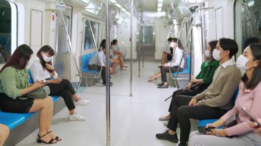 Kalabalık bir metroda maske takan insanlar.