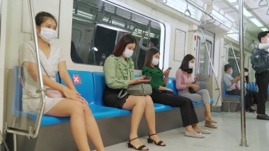 Kalabalık bir metroda maske takan insanlar.